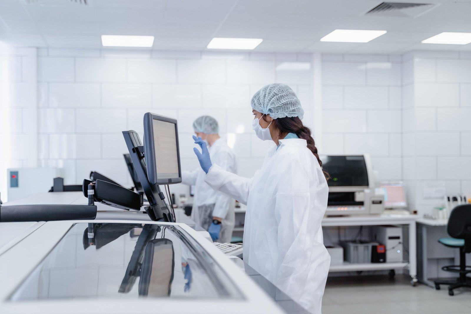 Lab technicians in protective gear operating computerized diagnostic equipment in a modern, fully automated laboratory